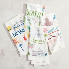 four napkins are laid out on a table top with the names of different cities printed on them