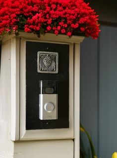 a flower box with red flowers in it and a fingerprint on the door handle