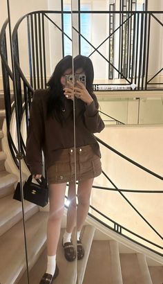 a woman taking a selfie while standing in front of a spiral staircase with her cell phone