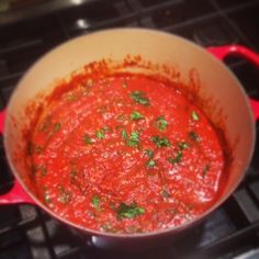 a pot filled with red sauce sitting on top of a stove next to an oven