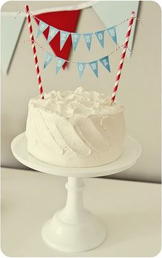 a cake with white frosting and red and blue bunting on top is sitting on a plate