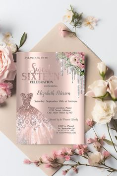 a pink and silver ball gown birthday party card with flowers on the table next to it