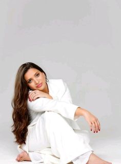 a woman sitting on the ground in white clothing