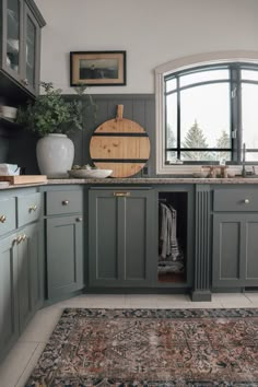 a kitchen with green cabinets and an area rug in front of the window that is open