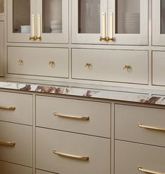 an elegant kitchen with marble counter tops and gold pulls on the cabinets, along with brass handles