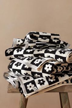 black and white patterned towels stacked on top of a wooden stool with a brown wall in the background