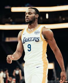 a male basketball player in a white and yellow uniform is holding his hand out to the side