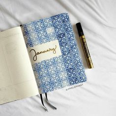 an open notebook with the word january written in cursive writing next to a pen