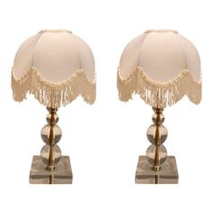 a pair of lamps with tassels on each end and a white lamp shade