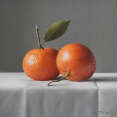 two oranges sitting on top of a white table cloth