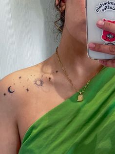 a woman with a sun and stars tattoo on her chest holding up a cell phone