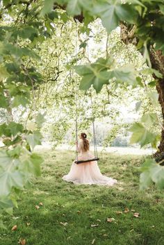 a woman sitting on a swing in the grass