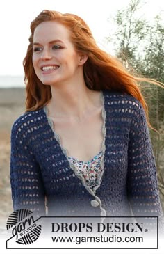 a woman with red hair wearing a blue crochet cardigan and smiling at the camera