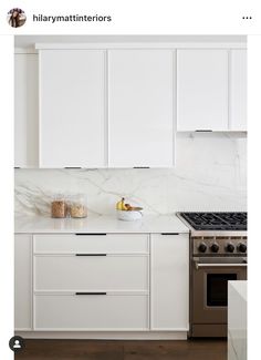 a kitchen with white cabinets and marble counter tops