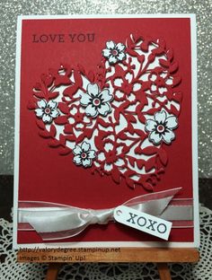 a red card with white flowers on it and a bow at the bottom that says i love you