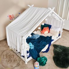 a child's bed with a canopy over it and stuffed animals on the floor