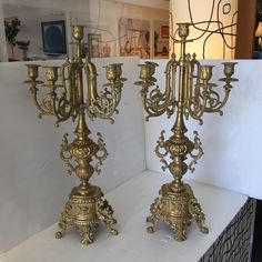 two brass candelabra on display in a store