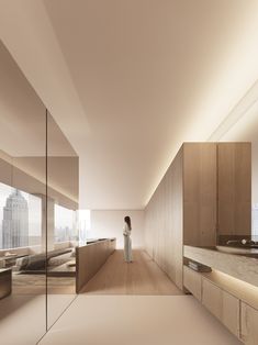 a woman is standing in the middle of a room with large windows and wooden cabinets