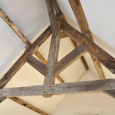 an old wooden structure in the middle of a room with white walls and wood beams