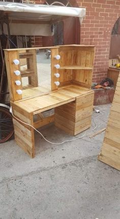 a wooden desk and mirror sitting on top of a cement floor next to a brick wall