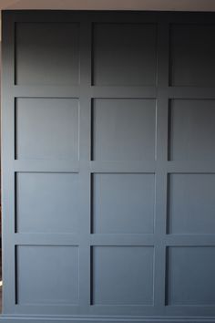 an empty room with blue painted walls and wood flooring in the background, there is a cat laying on the floor next to the door