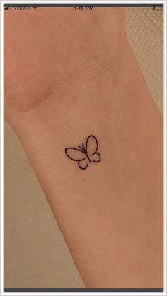 a small butterfly tattoo on the left side of the wrist is shown in black ink