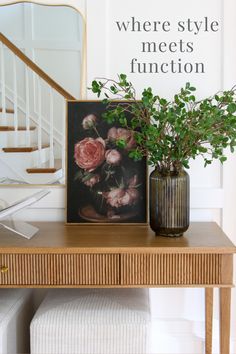 there is a vase with flowers on the table next to a framed photo and stairs