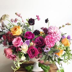 a white vase filled with lots of colorful flowers