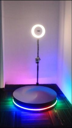 an illuminated object is on the floor in front of a white wall and purple light