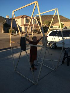 a young boy standing in front of a metal structure on the side of a road