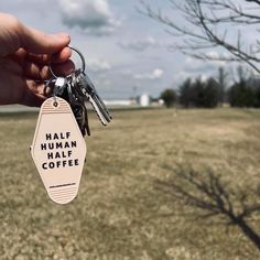 a hand holding a keychain that says half human half coffee on the outside