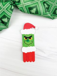 an ornament made to look like the grin face on top of a green scarf