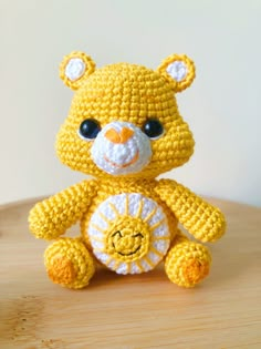 a yellow crocheted teddy bear sitting on top of a wooden table