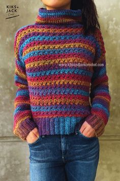 a woman wearing a multicolored sweater with her hands in her pockets and looking at the camera