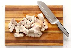 chopped up meat on a cutting board with a large knife next to the chopping block