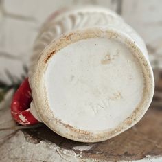 a white plate with red handles sitting on top of a piece of wood next to a plant