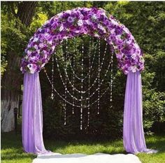 the wedding arch is decorated with purple and white flowers, beads, and pearls on it