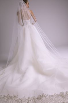 a woman in a wedding dress with a veil on her head is looking down at the floor