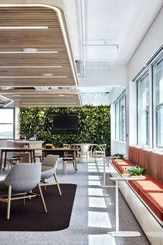 an office with plants on the wall and tables in front of it, along with couches and chairs