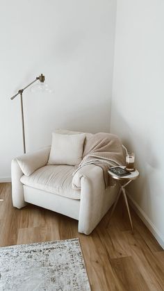 a white couch sitting on top of a hard wood floor next to a lamp and rug