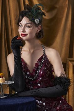 a woman in a red dress and black gloves holding a piece of cake on a plate