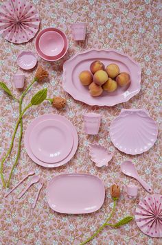 pink dishes and plates are arranged on a floral tablecloth