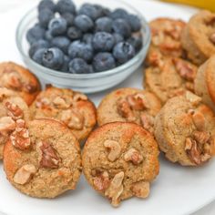 blueberries and muffins are on a plate next to a bowl of fruit