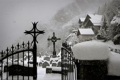 a black and white photo of a cemetery in the snow with a cross on it