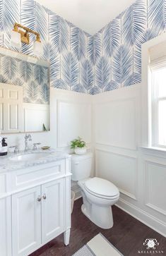 a bathroom with blue and white wallpaper on the walls, along with a toilet