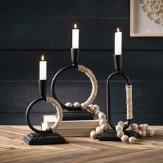 three candles are sitting next to each other on a wooden table with black and white decorations