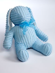 a blue teddy bear with a bow on it's head sitting against a white background