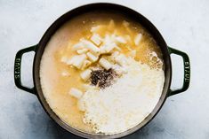 a pot filled with food on top of a white counter next to a wooden spoon