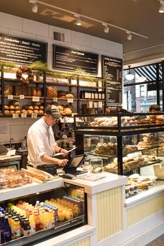 people are standing in line at the counter of a bakery with many items on display