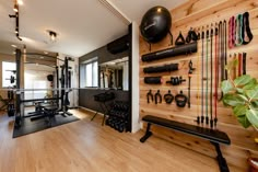 a home gym with various exercise equipment on the wall and wooden flooring in front of it